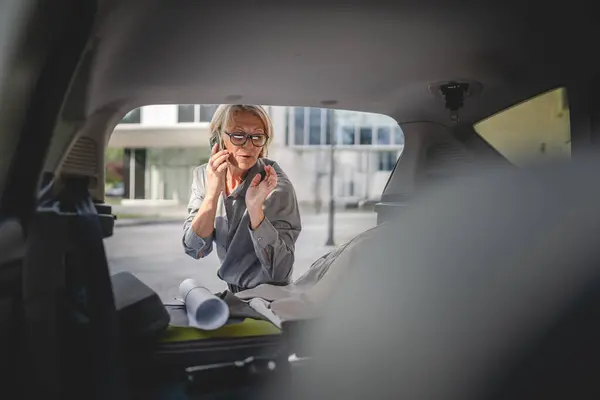 One mature blonde beautiful business woman travel concept female take stuff belongings from the back of her car while moving or arrive to destination or work real people copy space