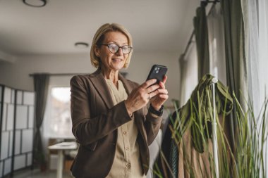 Yetişkin bir beyaz kadın cep telefonuyla mesaj atıyor.