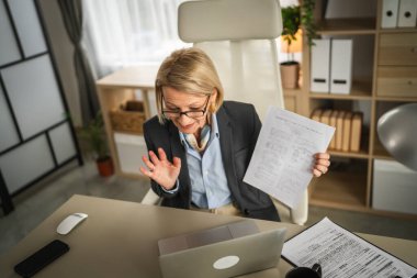 Olgun sarışın iş kadını, internet üzerinden danışmanlık ya da konferans kağıdı belge sözleşmesi ya da istatistikleri için bilgisayarını kullanabiliyor.