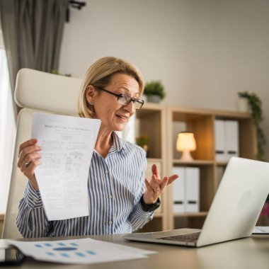 Olgun sarışın iş kadını, internet üzerinden danışmanlık ya da konferans kağıdı belge sözleşmesi ya da istatistikleri için bilgisayarını kullanabiliyor.
