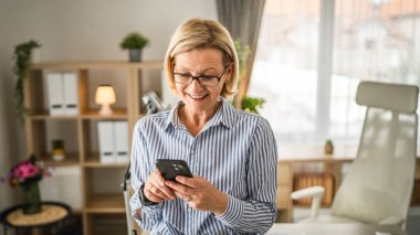 Yetişkin bir beyaz kadın cep telefonuyla mesaj atıyor.