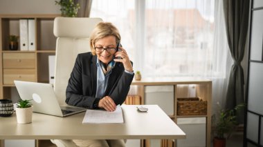 Olgun kadın işi. İş yerinde telefon et. Gülümse.