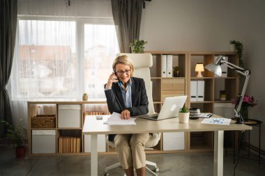 Olgun kadın işi. İş yerinde telefon et. Gülümse.