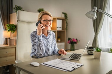 Olgun kadın işi. İş yerinde telefon et. Gülümse.