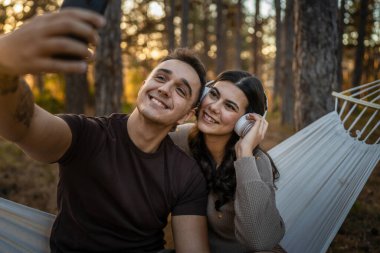 Doğadaki erkek ve kadın yetişkin çift kendi portresini çekerler. Çirkin resim. Cep telefonu kullanırlar ya da video görüşmesi yaparlar.