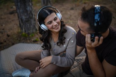 Erkek ve kadın, genç yetişkin bir çift kulaklıkla müzik dinliyor.