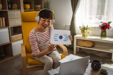 Yetişkin kadın Japon iş kadını video araması yapar ev içi internet danışmanlığı ya da konferans kağıdı belge sözleşmesi ya da istatistikleri gösterir.