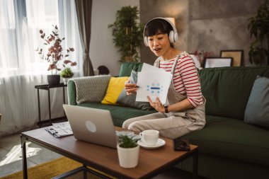 Yetişkin kadın Japon iş kadını video araması yapar ev içi internet danışmanlığı ya da konferans kağıdı belge sözleşmesi ya da istatistikleri gösterir.