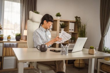 Olgun Japon kadın belgeleri elinde tutuyor ve video aracılığıyla danışmanlık yapıyor.