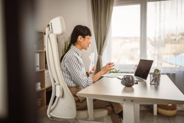 Olgun Japon kadın belgeleri elinde tutuyor ve video aracılığıyla danışmanlık yapıyor.