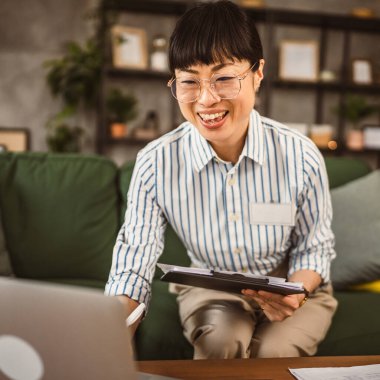 Olgun Japon kadın not panosunu tut ve evde çalışırken bilgisayarı kullan.