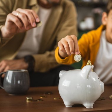 Baba, oğluna evdeki kumbarada nasıl para biriktireceğini göster.