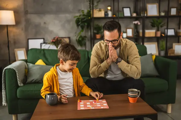 眼鏡と息子の慎重な遊びボードゲームと父親は彼が負けている怒っている原因 — ストック写真