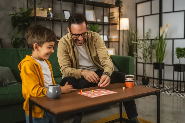 眼鏡と息子の慎重な遊びボードゲームと一緒に自宅で楽しい ロイヤリティフリーのストック画像