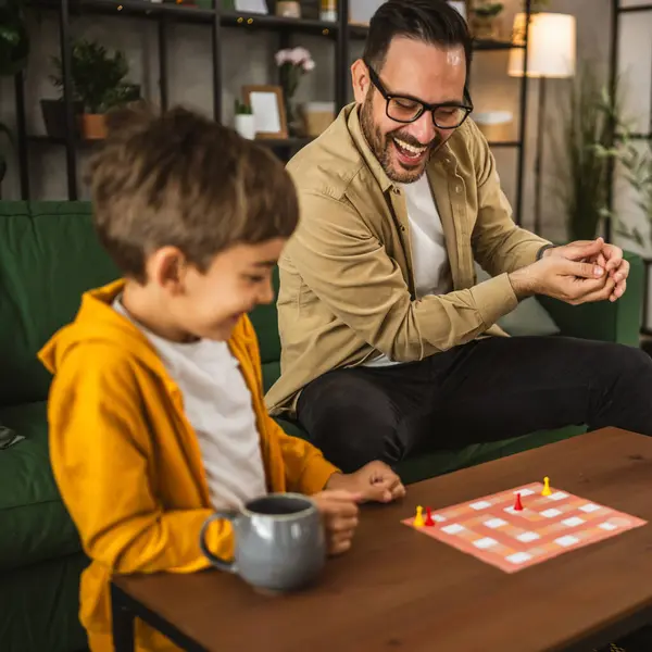 眼鏡と息子の慎重な遊びボードゲームと一緒に自宅で楽しい ロイヤリティフリーのストック写真