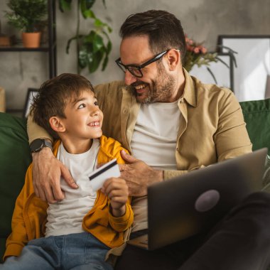 Baba ve oğlu Kafkasyalılar evdeki bilgisayarlarında kredi kartıyla online alışveriş yapıyorlar.