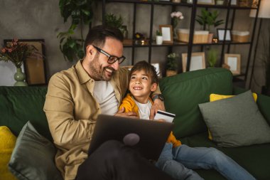 Baba ve oğlu Kafkasyalılar evdeki bilgisayarlarında kredi kartıyla online alışveriş yapıyorlar.