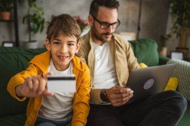 Baba ve oğlu Kafkasyalılar evdeki bilgisayarlarında kredi kartıyla online alışveriş yapıyorlar.