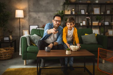 Baba ve oğlu Kafkas futbol maçı izleyip evde tezahürat yapıyorlar. Gürültülü, heyecanlı, mutlu.