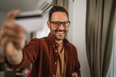 İnternette cep telefonuyla alışveriş yapan yetişkinlerin portresi ve evde kredi kartı bulundurmak.