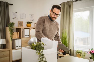Yetişkin, mutsuz, gözlüklü bir beyaz adam işten kovulduktan sonra eşyalarını ofiste topluyor.