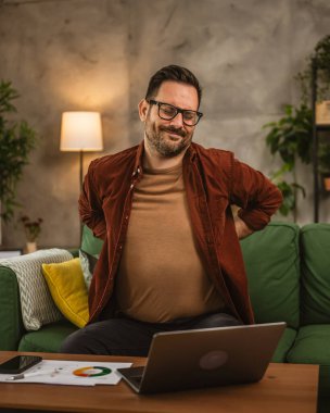 Yorgun bir yetişkin adam evde çalışırken sırt ya da böbrek ağrısı çeker.