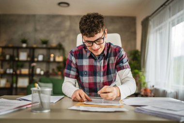 Genç beyaz adam otur ve evdeki okul anketini çöz.