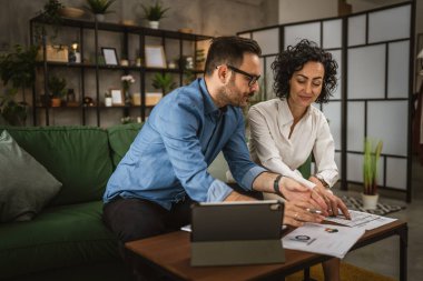 İki meslektaş erkek ve kadın evde ekonomi projesinde birlikte çalışıyorlar.