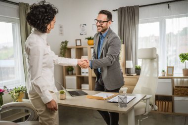 Olgun bir kadın ofiste oturup müdürle ya da patronla iş görüşmesi yapar.