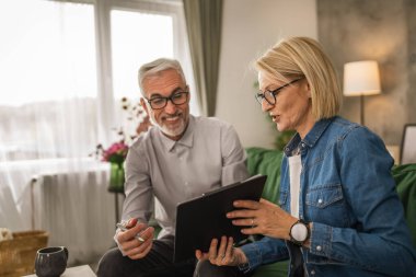 Olgun yaşlı kadın, kocaya evdeki evrakların nerede imzalanacağını gösterir.