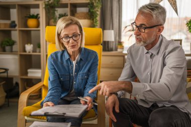 Olgun kıdemli koca, kadın karısına evrakların nerede imzalanacağını gösterir.