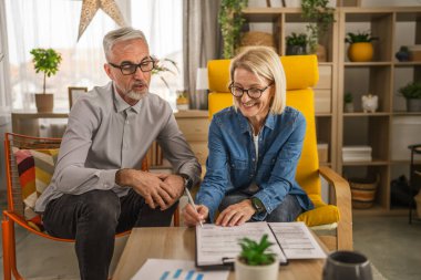 Olgun yaşlı kadın sigorta, sözleşme ya da faturayı evde imzalar.