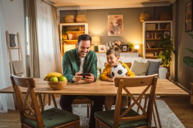 Baba ve oğlu Kafkas futbol maçı cep telefonuyla ve tezahürat mutfakta gürültülü, heyecanlı, mutlu