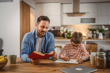 Babanın kitap yardımı ve oğlunun ödevlerine yardım etmesi.