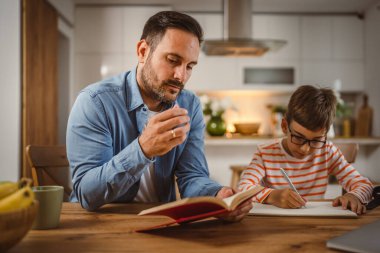 Babanın kitap yardımı ve oğlunun ödevlerine yardım etmesi.