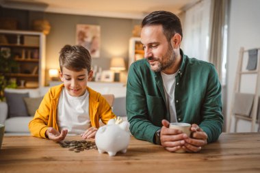 Baba ve oğul evdeki kumbarada birlikte para biriktiriyorlar.