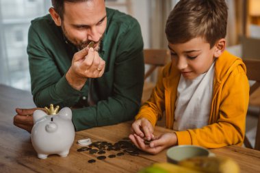 Baba ve oğul evdeki kumbarada birlikte para biriktiriyorlar.