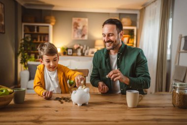 Baba ve oğul evdeki kumbarada birlikte para biriktiriyorlar.