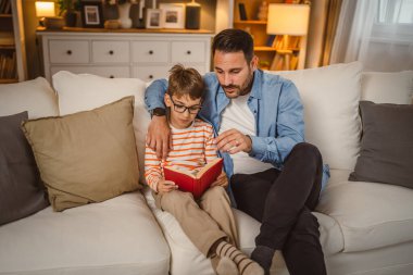 Baba ve oğlu Kafkasyalı bir kitap okuyor ve evde birlikte vakit geçirirken eğleniyorlar.