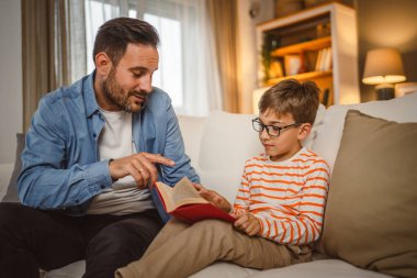 Baba ve oğlu Kafkasyalı bir kitap okuyor ve evde birlikte vakit geçirirken eğleniyorlar.