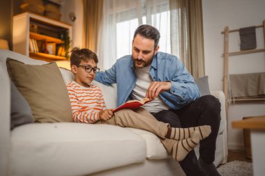 Baba ve oğlu Kafkasyalı bir kitap okuyor ve evde birlikte vakit geçirirken eğleniyorlar.