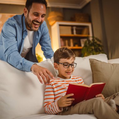 Baba oğluna bak nasıl kitap okuyor ve evde birlikte vakit geçiriyoruz.,