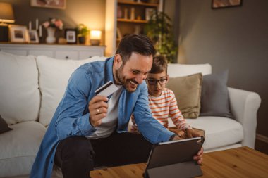 Babası kredi kartını elinde tutarken oğlu paketi elinde tutarken internetten tablet almış.