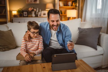 Babası kredi kartını elinde tutarken oğlu paketi elinde tutarken internetten tablet almış.
