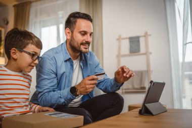 Babası kredi kartını elinde tutarken oğlu paketi elinde tutarken internetten tablet almış.
