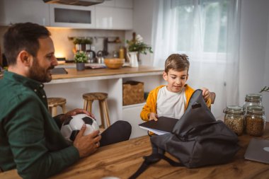 Genç çocuk okul için defterini ve kitabını sırt çantasına koy.