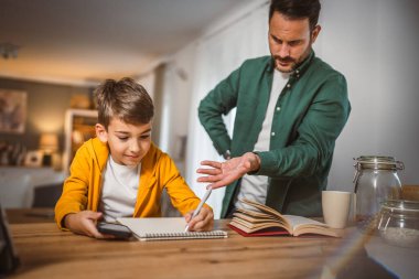 Öfkeli baba oğluna ödevlerini yapması için bağırıyor.