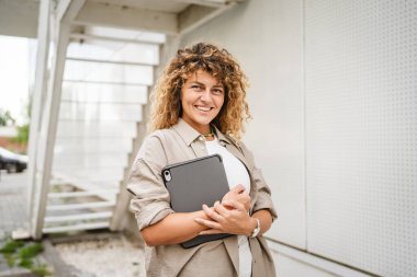 Yetişkin kadın portresi ayakta durup tablet tutarken gülümseyin.