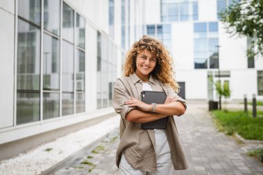 Yetişkin kadın portresi ayakta durup tablet tutarken gülümseyin.