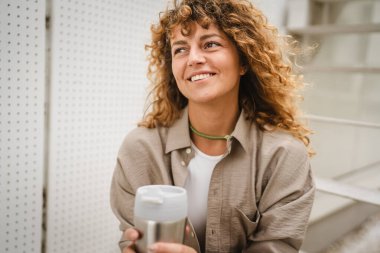 Kadının portresi merdivenlerde oturur ve termos bardağını kahveyle tutardı.